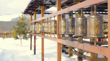 Bilinmeyen kadın, soğuk kışın Sibirya 'da tapınak kompleksi Rinpoche Bagsha' da Tibet mantrası ile dua tekerleklerini yuvarlıyor.