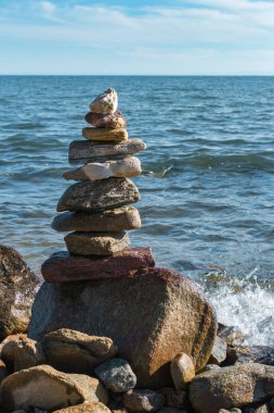Yaz güneşli bir günde, Baykal Gölü 'nün iç dalgaları üzerinde istiflenmiş taş piramidi, güzel manzaralı deniz manzarası, istikrar, denge ve uyum kavramı, dikey görüntü.