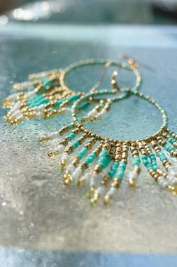 Turkuaz boho mücevher küpeleri camda pırıltı damlaları, plaj tatili için yaz aksesuarları, deniz konsepti tropikal deniz mücevherleri, düşük açılı parlak dikey görüntü