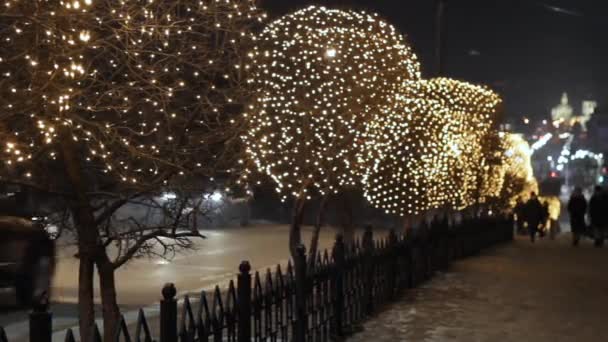 Iluminación decorativa nocturna en árboles por carretera, luces de guirnalda de Navidad y coches en camino de tráfico — Vídeo de stock