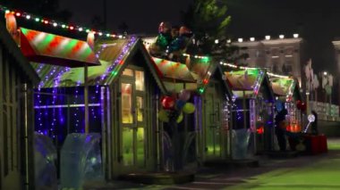 Karanlık gecelerde şehir Noel pazarı, çelenk ışıkları ve Noel fuarında aydınlanma.