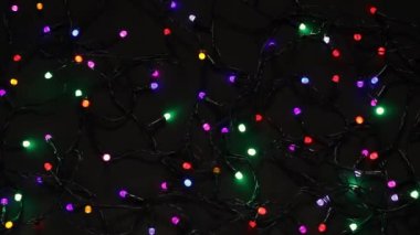 Yılbaşı dekoratif çelenklerinin bayram arkaplanı. Siyah arka planda. Çok renkli xmas ışıklarının ışıltısı.