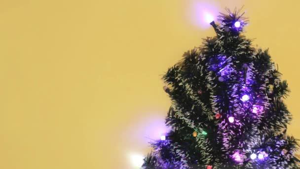 Різдвяні Вогні Миготять Різними Кольорами Зверху Ялинку Жовтому Тлі Святкових — стокове відео