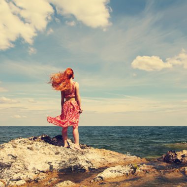 okyanus kıyısında bir elbiseli kızıl saçlı genç kadın