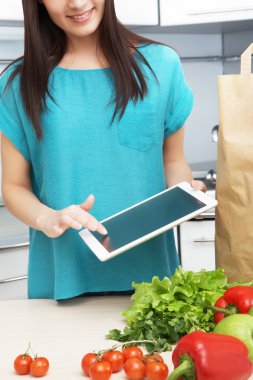 ev hanımı bir tablet bilgisayar mutfakta kullanır.