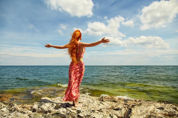 Roodharige jonge vrouw in een jurk aan de Oceaan kust — Stockfoto