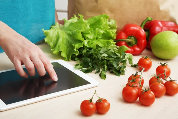 Ama de casa utiliza una tableta en la cocina —  Fotos de Stock