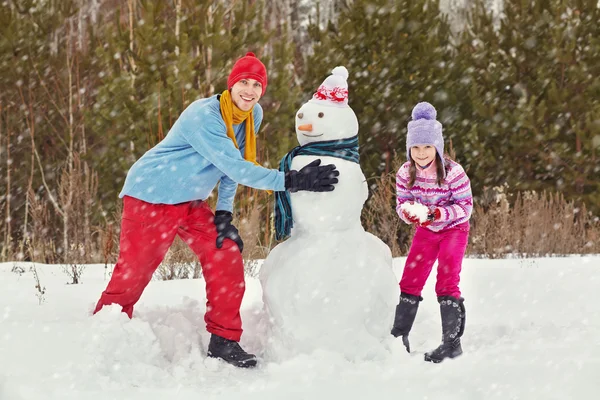 Vater und Tochter mit Schneemann — Stockfoto