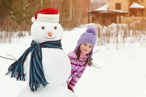 Kind spielt mit Schneemann — Stockfoto