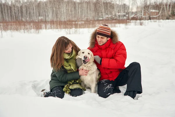 Portret młodej pary z psem na zimowym spacerze. mężczyzna i kobieta z labradorem — Zdjęcie stockowe