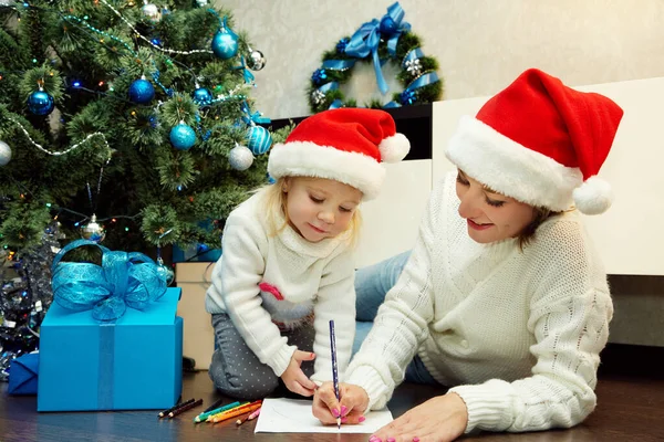 Glückliche Mutter und kleine Tochter schreiben einen Brief an den Weihnachtsmann — Stockfoto