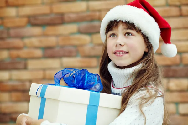 Linda adolescente feliz en sombrero de santa celebración de una caja de regalo. niño de Navidad. — Foto de Stock