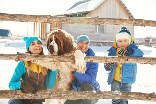 Glücklich spielende Familie mit Bernhardinerhund im Winter. Menschen im Freien — Stockfoto