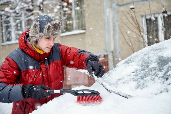 Um homem a escovar a neve do pára-brisas do seu carro Imagens De Bancos De Imagens Sem Royalties