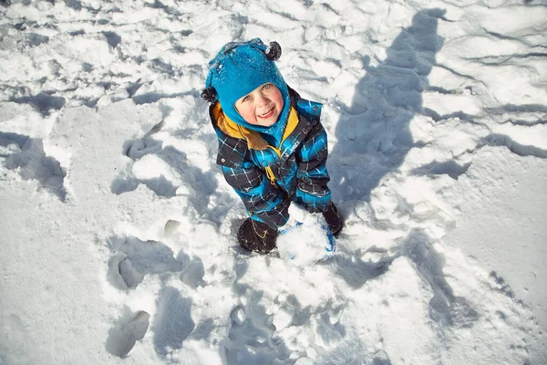 Komik küçük çocuk kışın karla oynuyor. — Stok fotoğraf