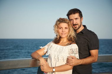 Birbirine aşık çiftler deniz kıyısında yürüyor.