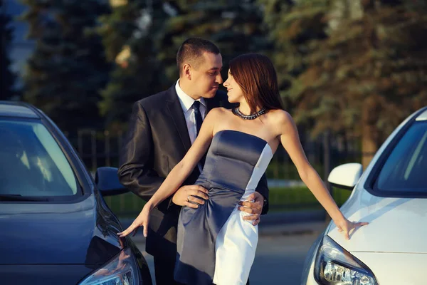 Retrato de una pareja joven en una cita de pie cerca de los coches. — Foto de Stock