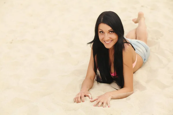 Jovem bela menina sexy em swimwear deitado em uma praia de areia. — Fotografia de Stock