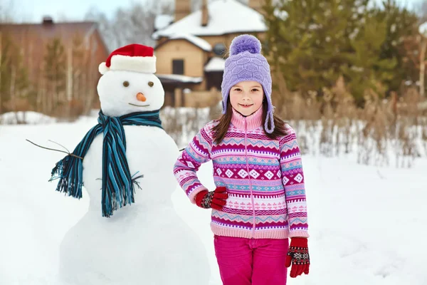 Miúdo brincando com boneco de neve — Fotografia de Stock