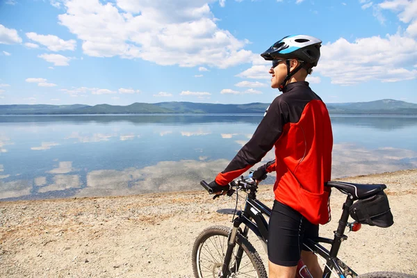 Muž s kolo na horské jezero — Stock fotografie