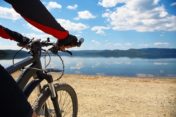 Man with bike on a mountain lake — Stock Photo, Image