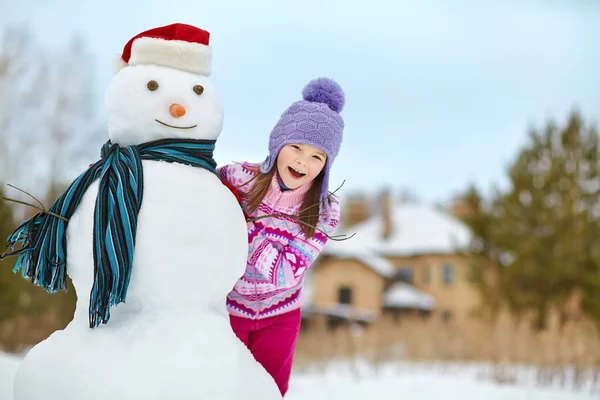 Kind spielt mit Schneemann — Stockfoto