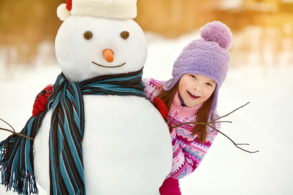 Miúdo brincando com boneco de neve — Fotografia de Stock