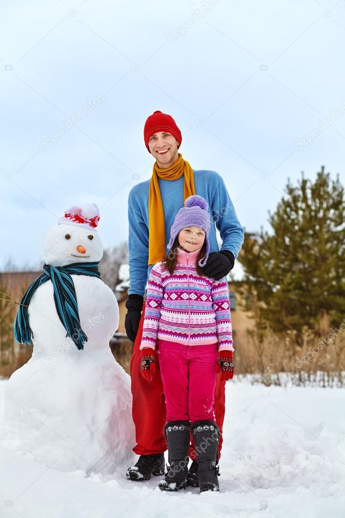 Father and daughter with snowman