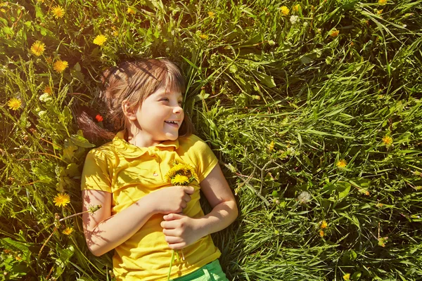 Girl sitting in the grass with dandelion — Stock Photo, Image