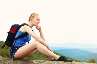 Sırt çantalı bir kadın dağda yürüyüş yapıyor.