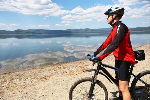 Uomo con bici su un lago di montagna — Foto Stock