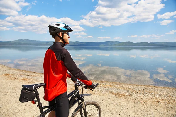Человек с велосипедом на горном озере — стоковое фото
