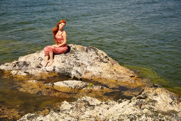 Рыжая молодая женщина в платье на берегу океана — стоковое фото
