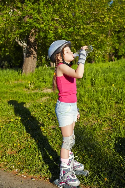 Liten flicka i rullskridskor i en park — Stockfoto