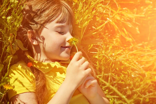 Meisje liggend in het gras met paardebloem — Stockfoto