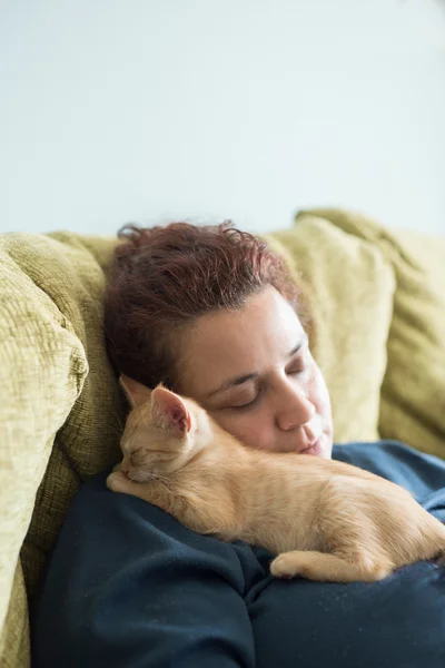 Orange tabby kitten sleeping in the lap of a woman — Stock Photo, Image
