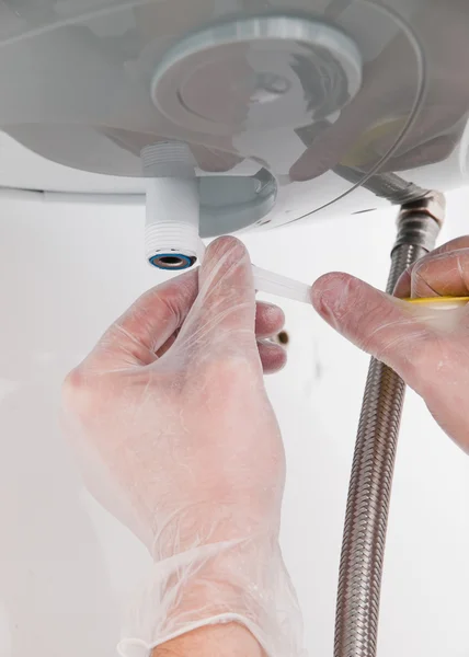 Hands repairing the plumbing pipes of an electric boiler — Stock Photo, Image