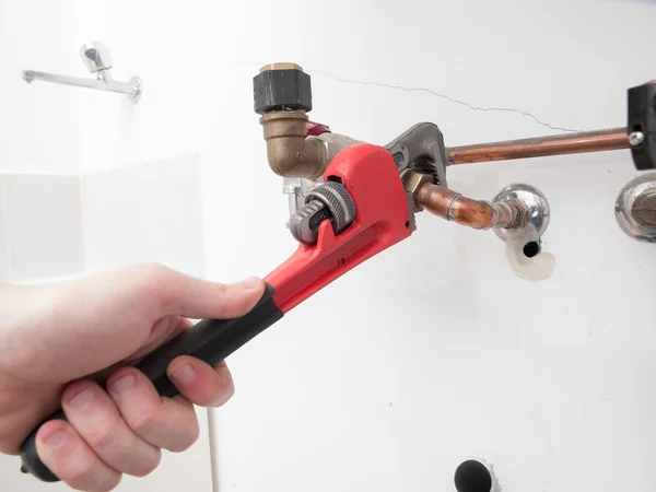 Mãos reparando os tubos de encanamento de uma caldeira elétrica — Fotografia de Stock