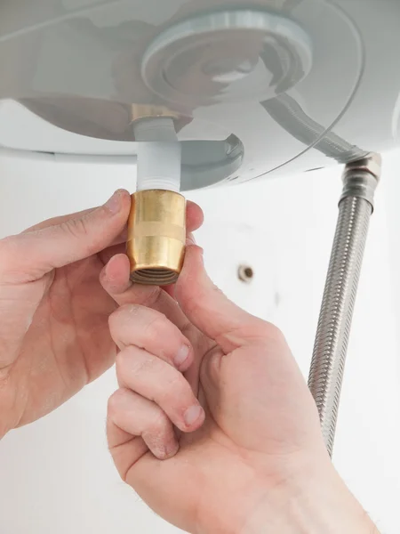 Hands repairing the plumbing pipes of an electric boiler. — Stock Photo, Image