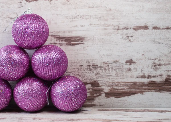 Roze kerstballen in een stapel op houten achtergrond — Stockfoto