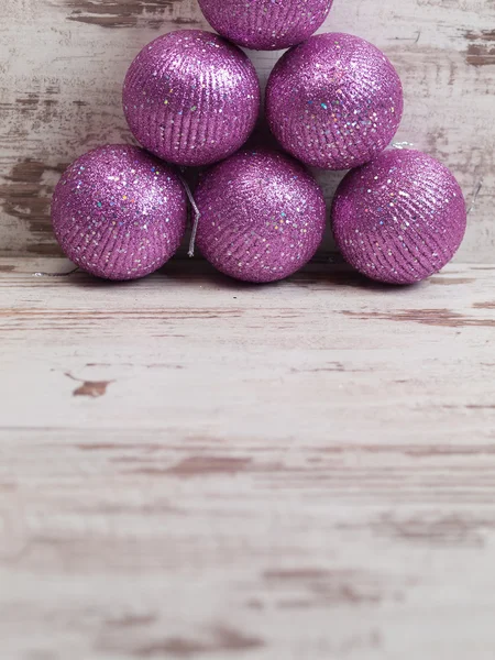 Boules de Noël roses dans une pile sur fond en bois — Photo