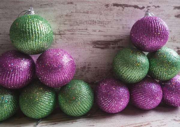 Bolas de Navidad rosas y verdes en una pila sobre fondo de madera —  Fotos de Stock