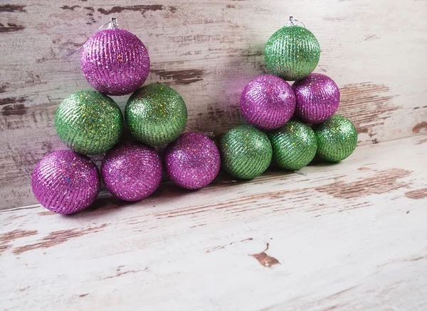 Bolas de Navidad rosas y verdes en una pila sobre fondo de madera —  Fotos de Stock