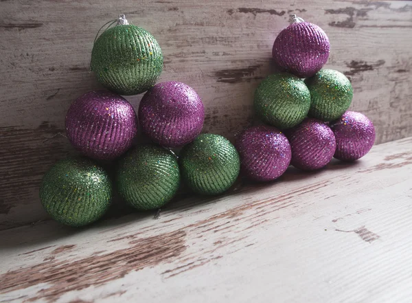 Roze en groene kerstballen in een stapel op houten achtergrond — Stockfoto