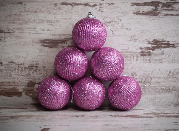 Roze kerstballen in een stapel op houten achtergrond — Stockfoto