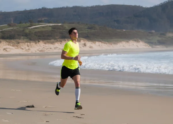 Jovem em roupa de fitness correndo ao longo da praia — Fotografia de Stock