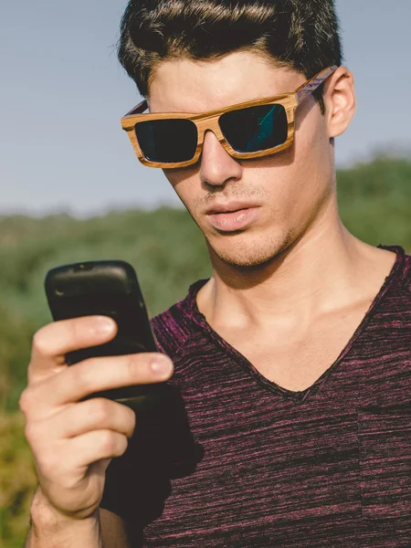 Model man portrait with wooden sunglasses outdoors. Man is using — Stock Photo, Image