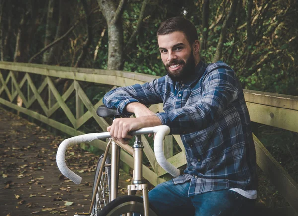 Hipster hombre con una bicicleta fixie y sonriendo — Foto de Stock