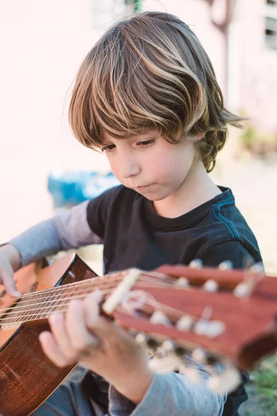 Blond liten pojke spelar spansk gitarr — Stockfoto