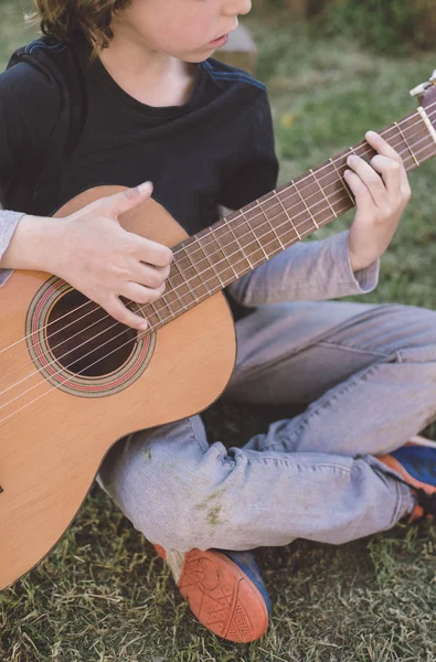 Liten blond pojke spelar spansk gitarr utomhus — Stockfoto